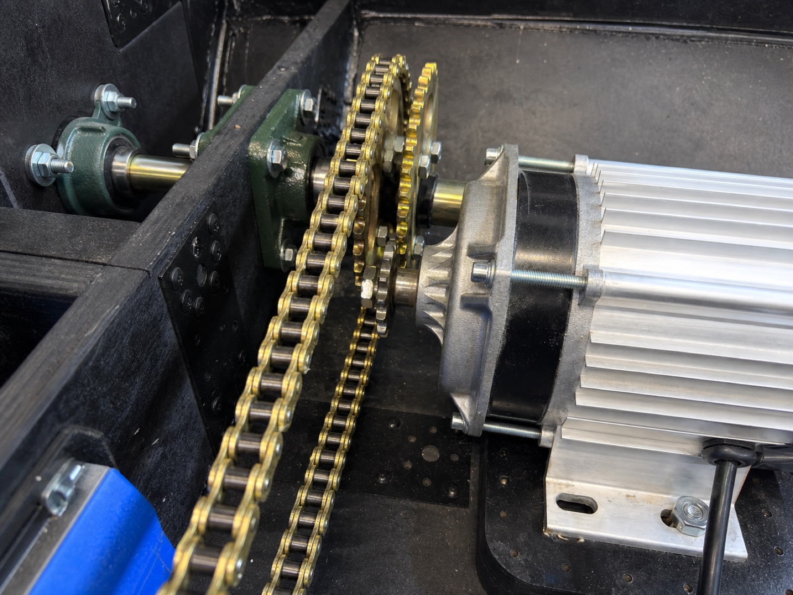 Reconstruction from a prototype photograph showing the HARDY electric gearmotor, dual chain transmission, shaft and industrial bearing interface